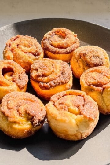 Plate of pumpkin spice cinnamon rolls made with puff pastry and coated in cinnamon sugar