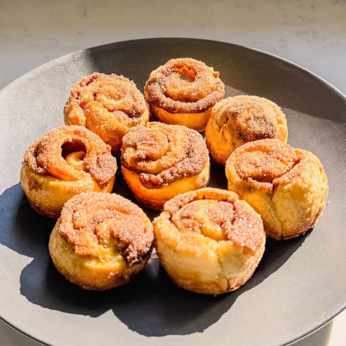 Plate of pumpkin spice cinnamon rolls made with puff pastry and coated in cinnamon sugar